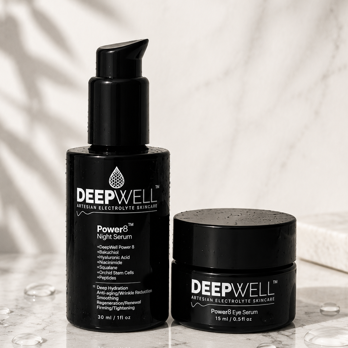 Two black-violet Deep Well skincare containers on a light marble surface: a pump bottle labeled Power6 Night Serum and a matching jar labeled Power6 Eye Serum, with a soft marble background and leaf shadows.