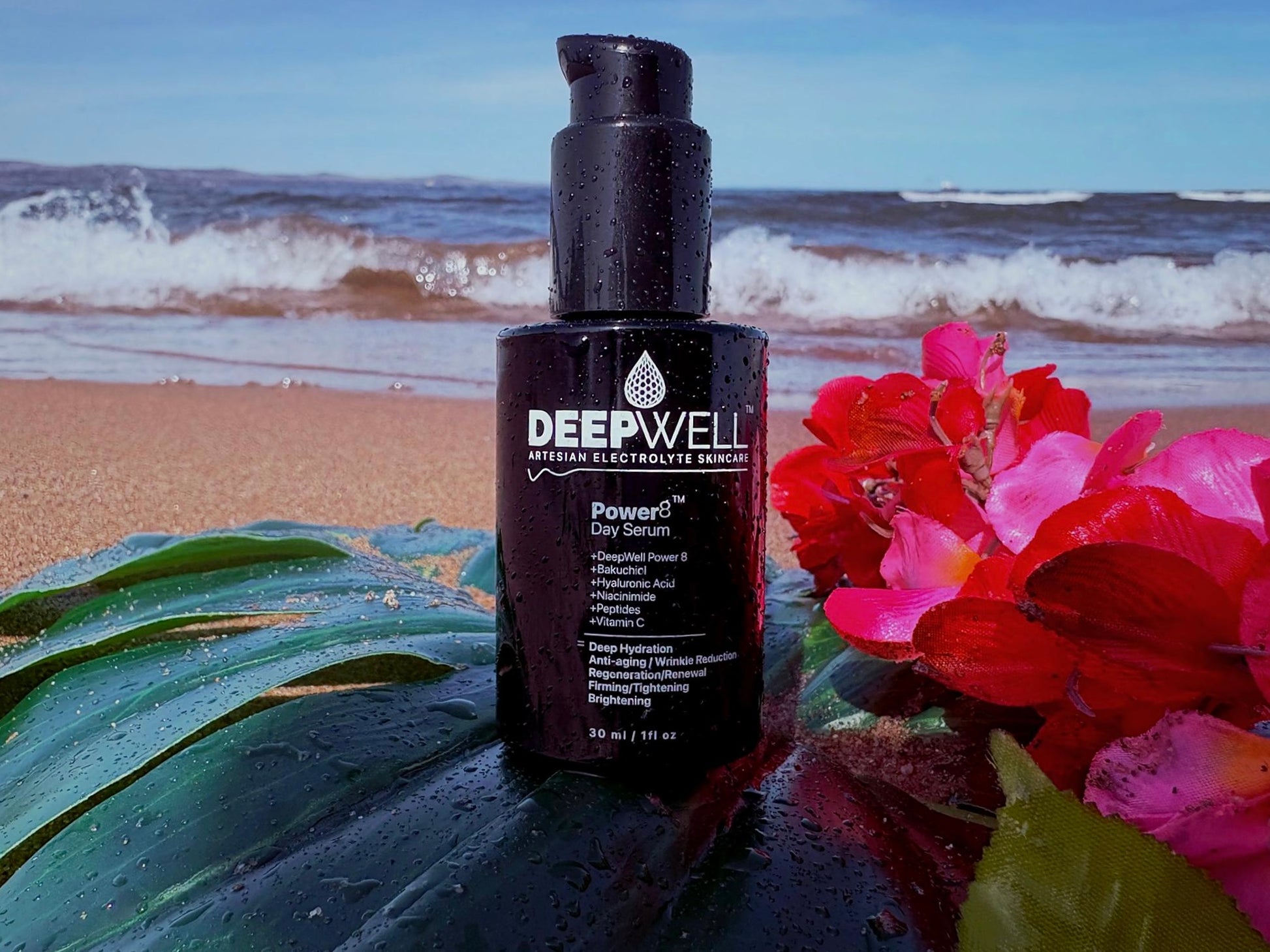 DeepWell Power8 Day Serum 30ml bottle on a beach with tropical flowers and ocean waves — powered by artesian electrolyte water