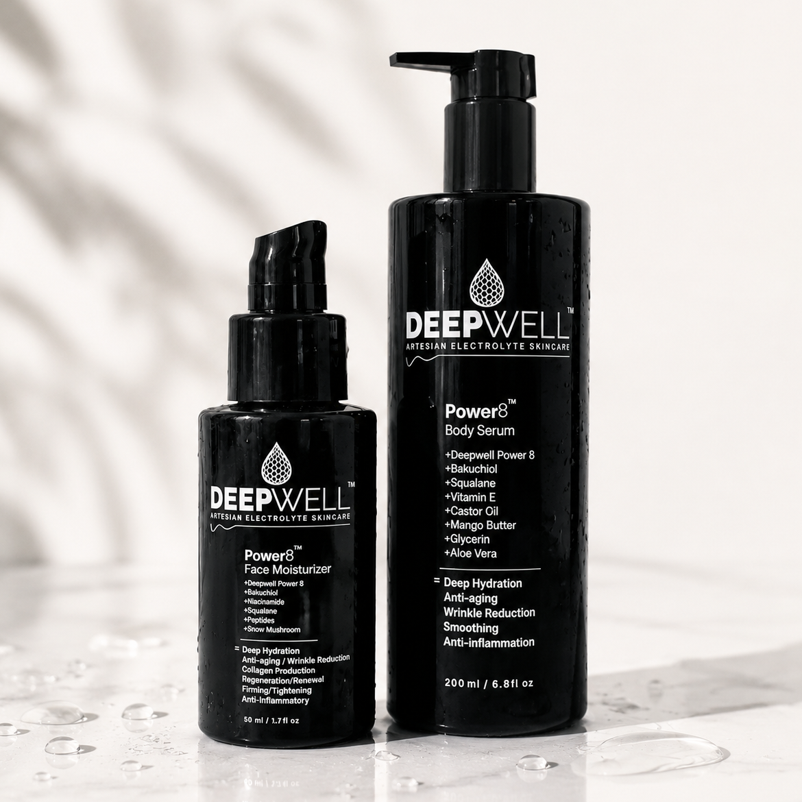 Two  black-violet Deepwell skincare bottles on a glossy white surface with water droplets. The taller bottle on the right is the Powers Body Serum, and the shorter bottle on the left is the Powers Face Moisturizer.